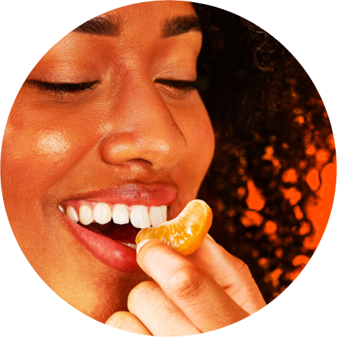 A woman biting a peeled piece of Peelz seedless California mandarins.