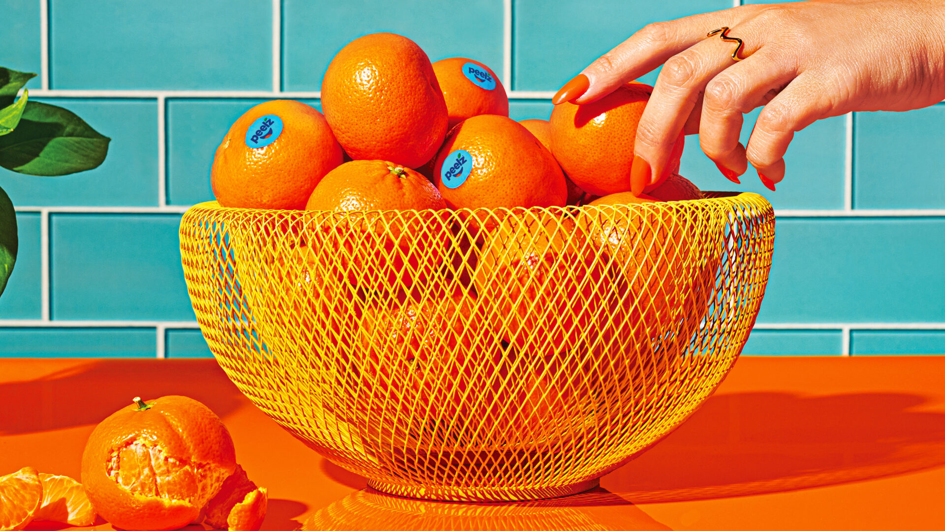 Hand reaching towards a bowl of Peelz mandarins